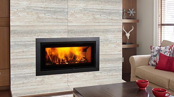 Regency Montrose Large Wood Fireplace installed on a wooden wall beside decor and sofa, one of the best wood heaters for autumn