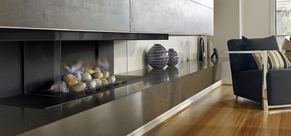 A modern Horizon Cantilever Fire with glass surround beside a stylish chair, one of the best gas log heaters for autumn