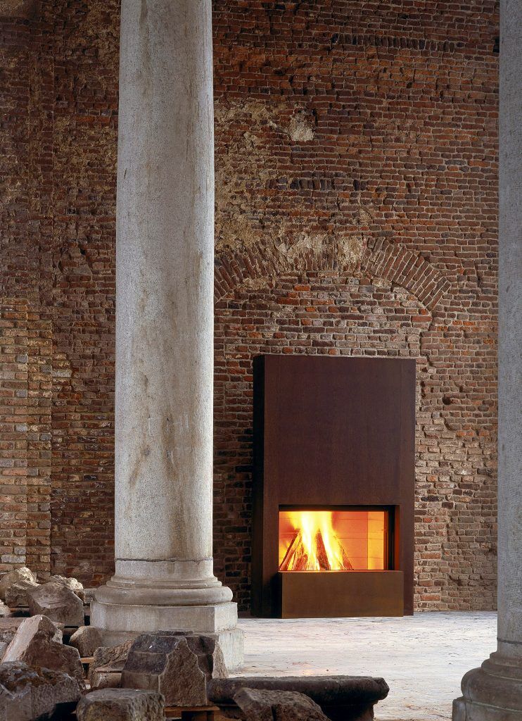 Stuv 21 inbuilt fireplace within a brick wall framed by stone pillars, showcasing modern wood fireplaces for home heating