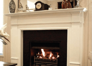 A Real Flame Montigo Windsor fireplace with a clock and vase on the mantelpiece, one of the best gas fireplaces for autumn warmth