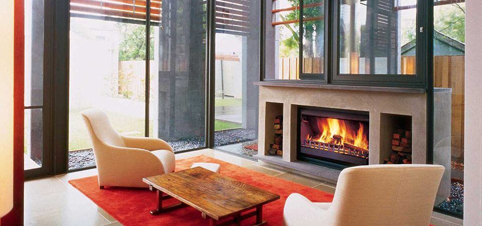 A living room with a Jetmaster Universal Inserts fireplace and soft couches, one of the best fireplaces for autumn warmth