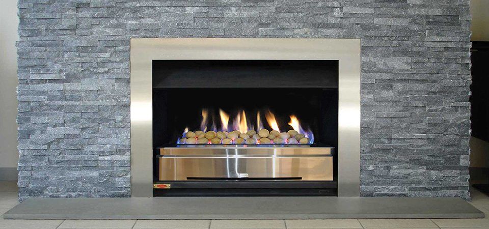 Jetmaster Topaz Series fireplace with blue flame beside a plush sofa, one of the best fireplaces for autumn warmth and style