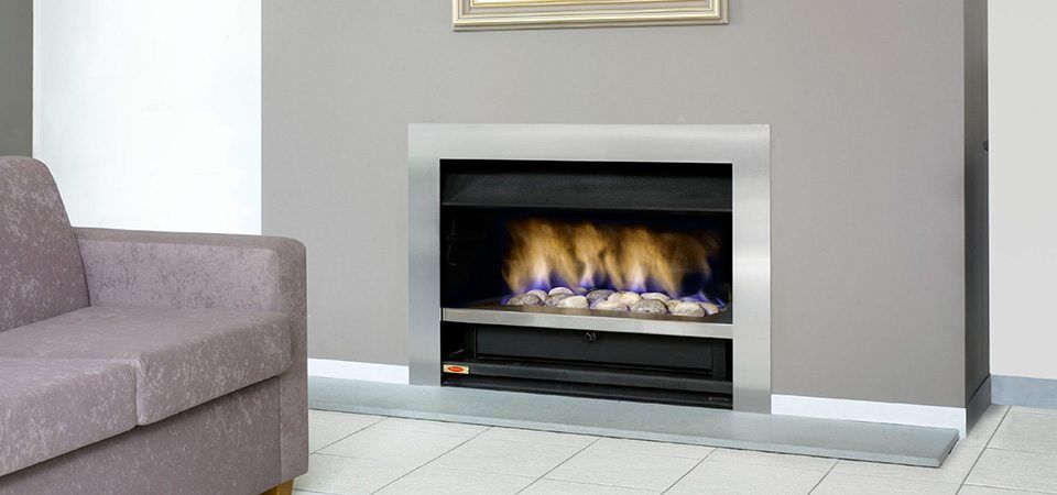 Jetmaster Topaz Series fireplace with blue flame beside a plush sofa, one of the best fireplaces for autumn warmth and style
