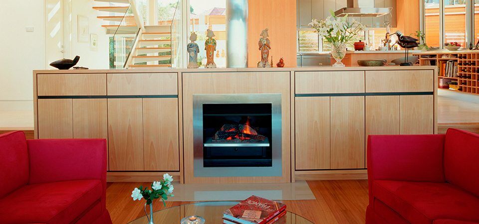 A cosy living room with a Jetmaster Topaz Series fireplace and red couches, one of the best fireplaces for autumn warmth