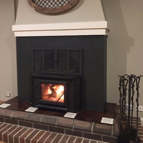 A brick fireplace with a Quadra Fire Heatilator WINS18 Insert and a solid brick hearth beneath, designed for efficient home heating