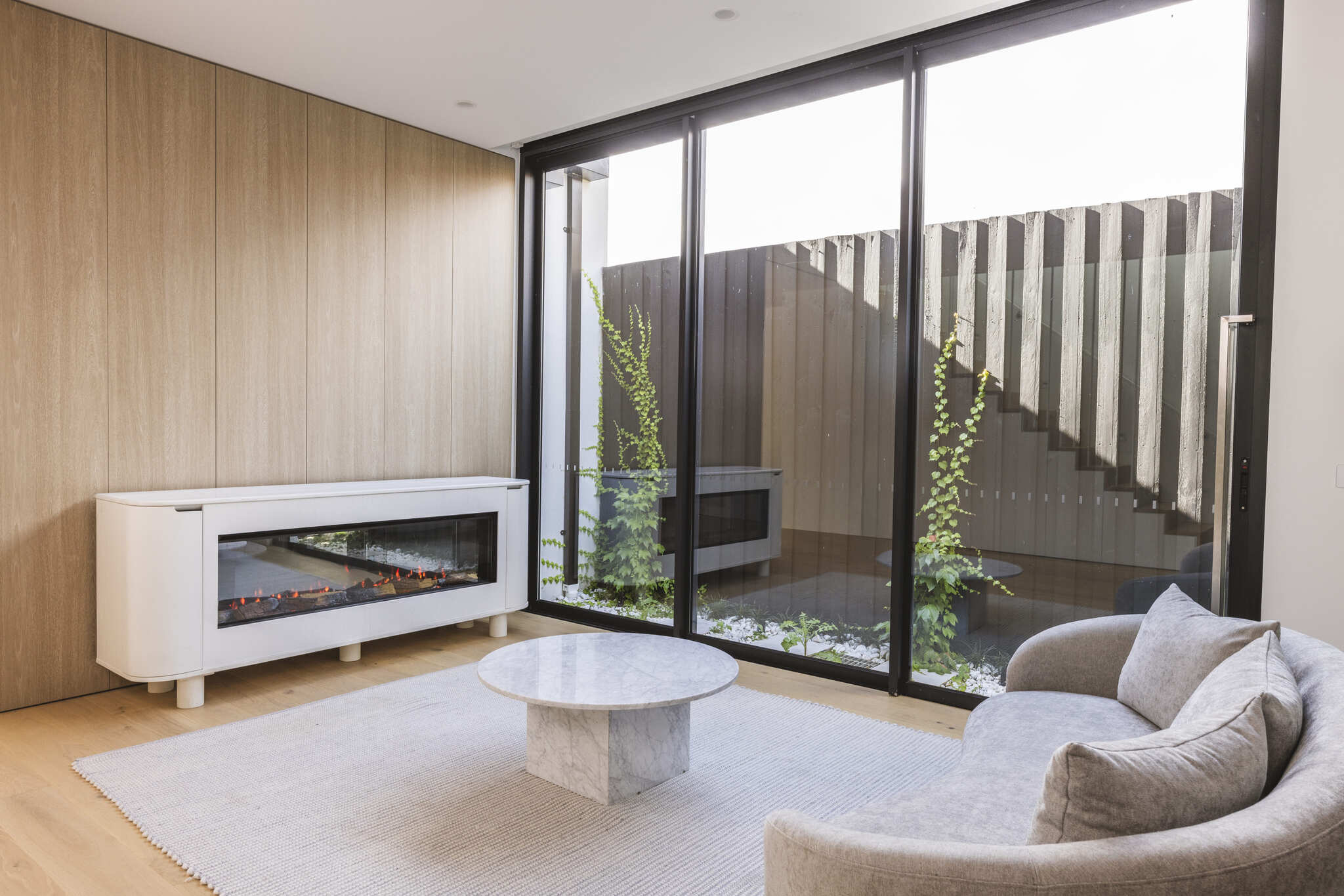 A modern living room with an electric fireplace and sliding glass doors, featuring the EmberArc Ashton 210 for a contemporary touch