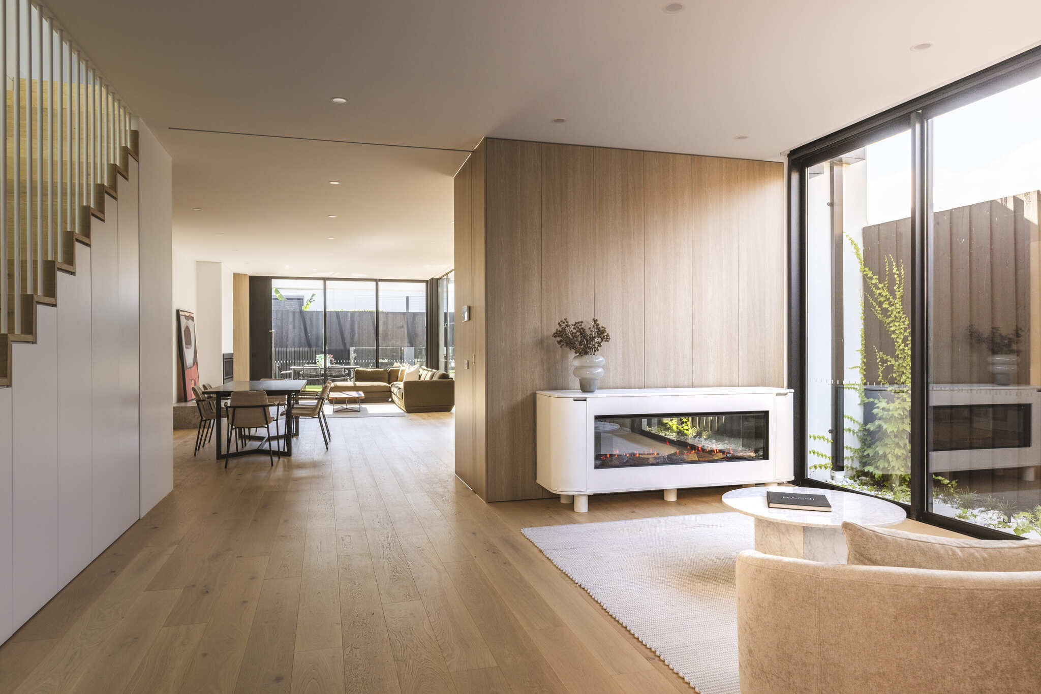 Contemporary living room with wood flooring and glass walls, styled with the Ember Arc Grange 180 electric fireplace architectural design
