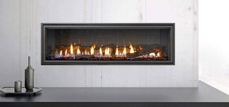 A Heat & Glo Mezzo Series fireplace with logs built into a white wall, offering warmth and style from modern gas log fires for homes