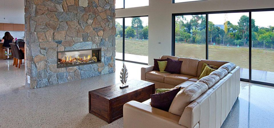 Elegant living room with a Heat & Glo Mezzo Series fireplace set in a stone wall, adding warmth and style with modern gas log fires for homes
