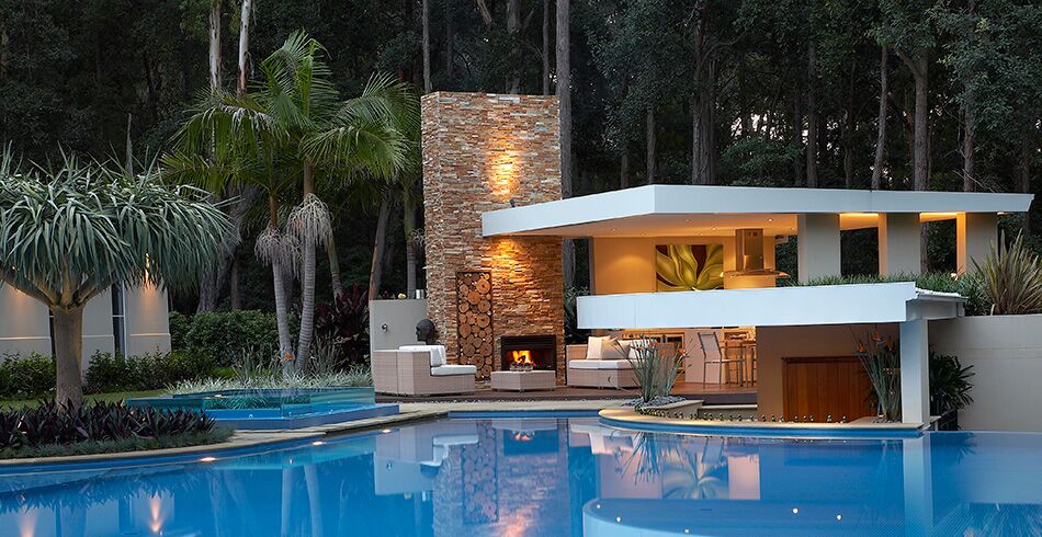 Modern home with a pool and open wood fireplace creating cosy warmth, showing the best wood heaters for autumn comfort