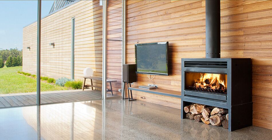 A stylish open wood fireplace in a modern living room with large glass window panels , one of the best wood heaters for autumn creating warmth and comfort