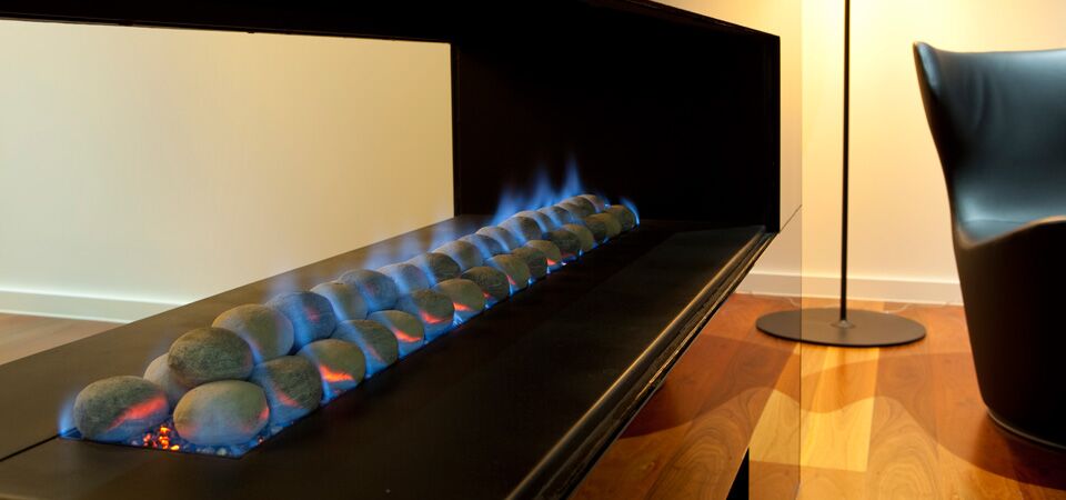 Modern gas log fires for homes with Horizon 3 Sided Fire emitting blue flames beside a stylish chair in a contemporary room