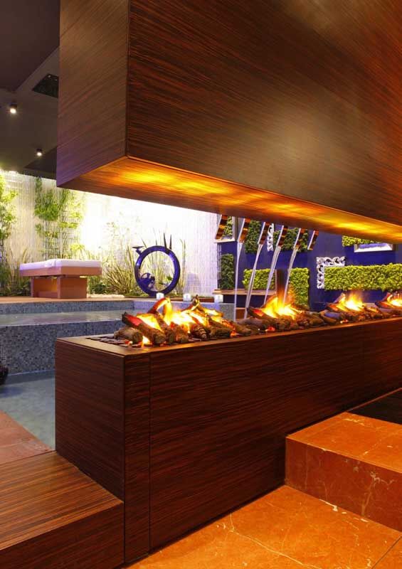 A sleek Optimyst unit from modern electric fireplaces for homes adds warmth and elegance beside a serene swimming pool
