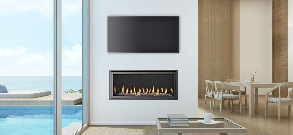 A modern Heat & Glo SLR-X flue gas fireplace in a living room with a stunning view of the ocean through large windows, one of the best gas log heaters for autumn