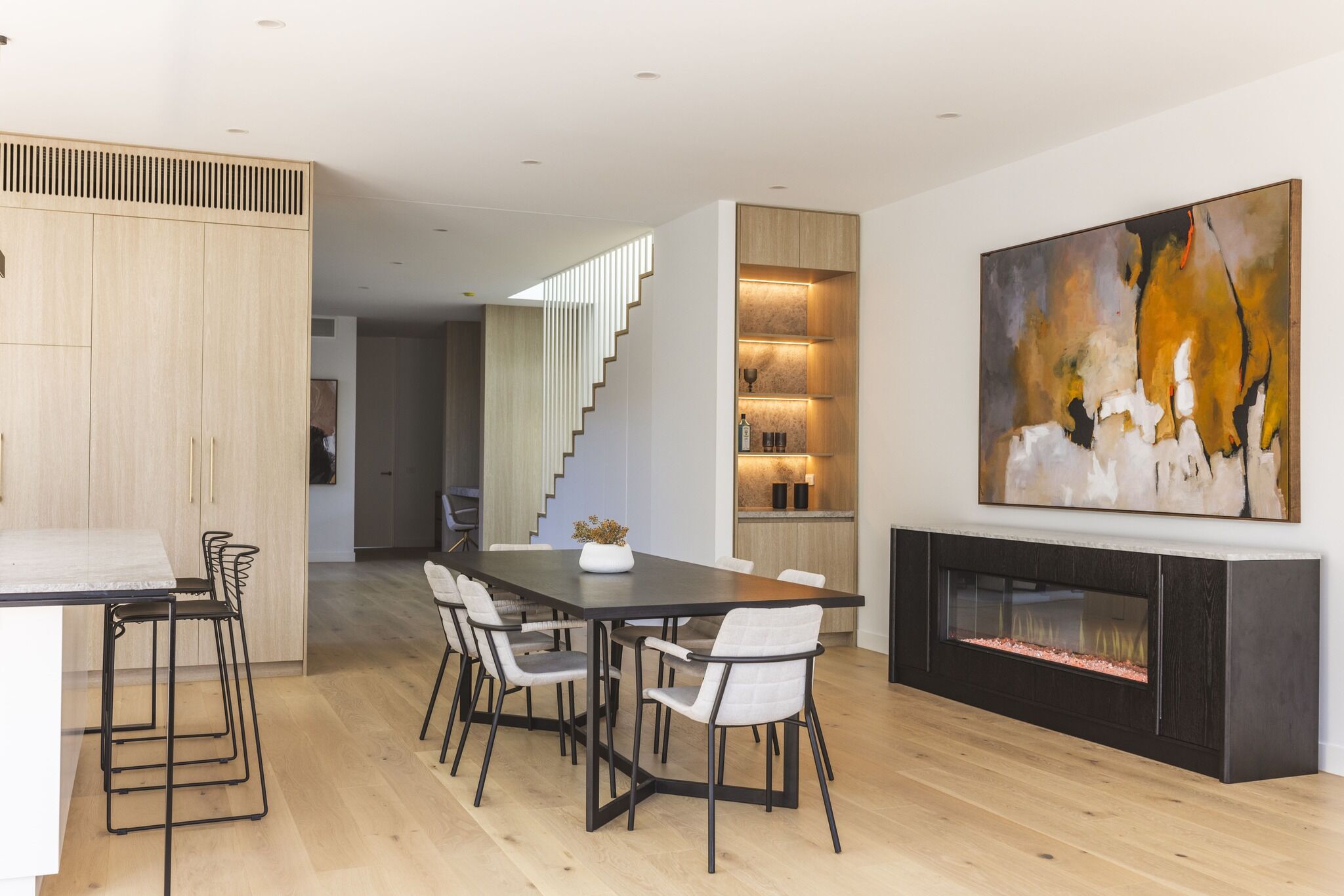 Modern dining room with an electric fireplace and artwork, with the Ember Arc Grange 240 integrated seamlessly into the interior design