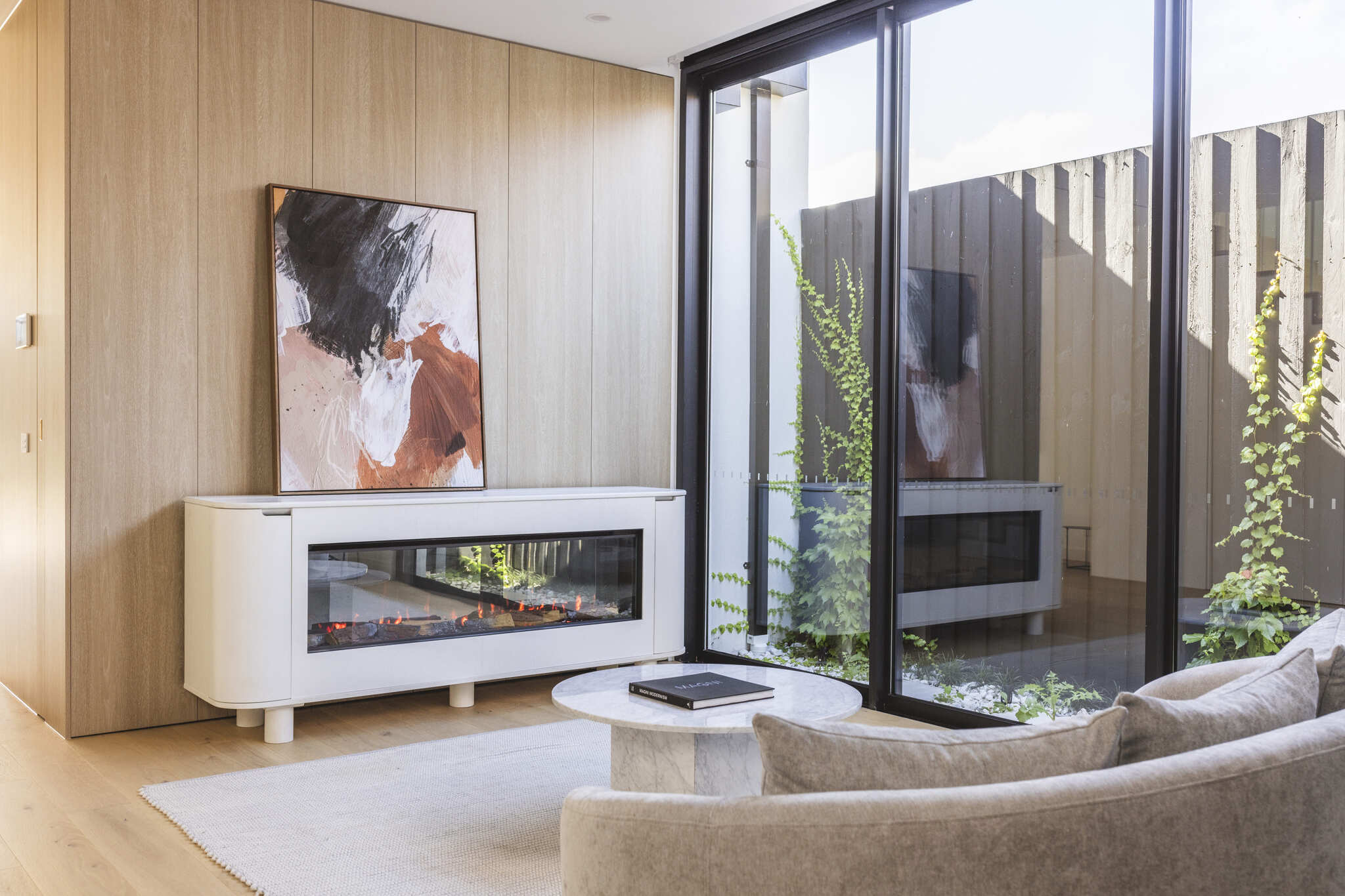 Modern living room with Ember Arc Grange 180 electric fireplace, a painting above, and large windows enhancing the open, stylish space