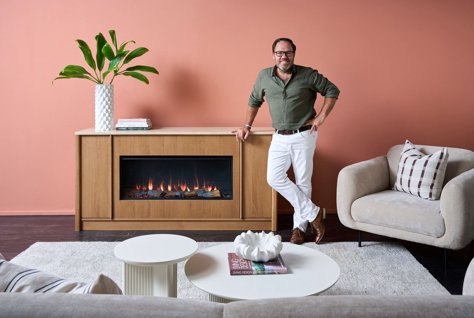 A man stands beside an electric fireplace in a cosy living room with the Ember Arc Grange 180 installed, adding warmth and style to the space