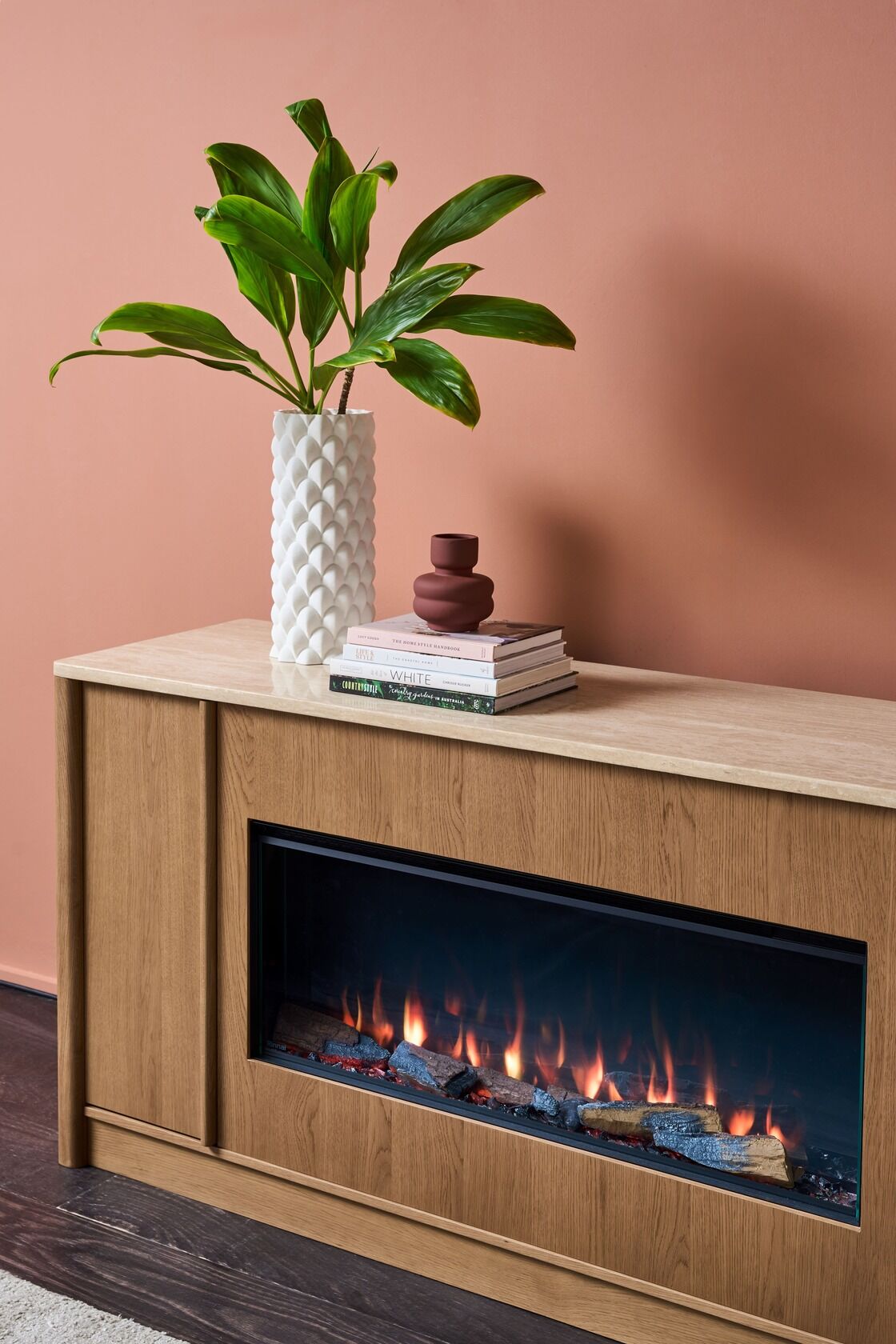 White vase on a wooden cabinet of Ember Arc Grange 180 electric fireplace in a cosy room with simple and elegant interior design