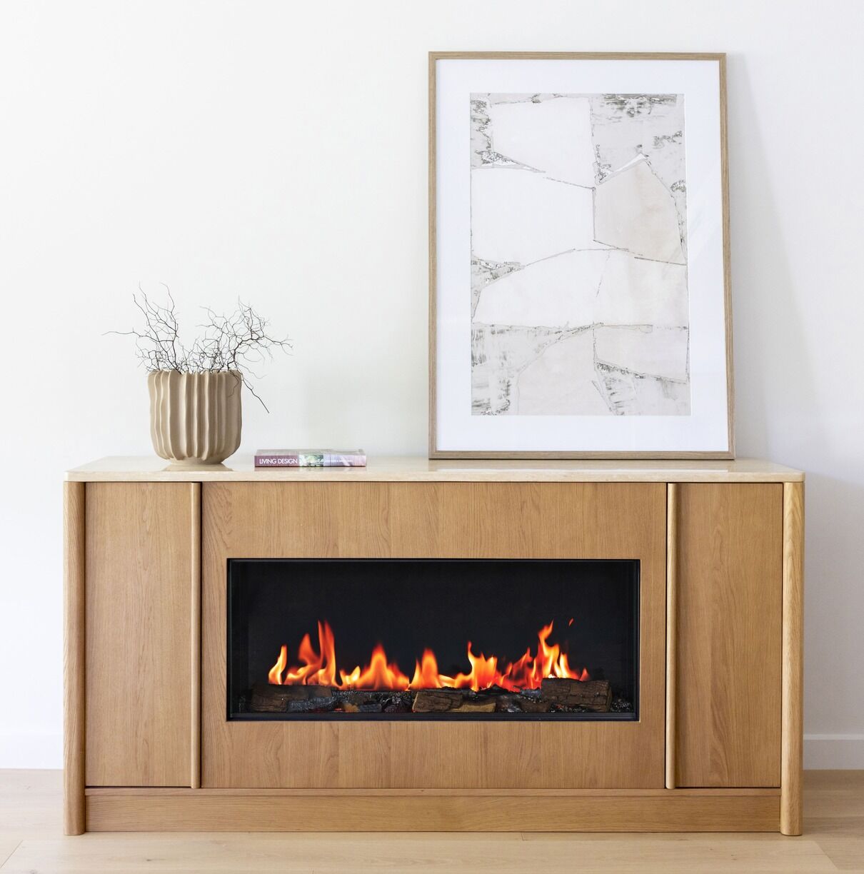 A painting and vase sit atop an Ember Arc Grange 180 electric fireplace with wood-burning insert, adding modern elegance and warmth to the space
