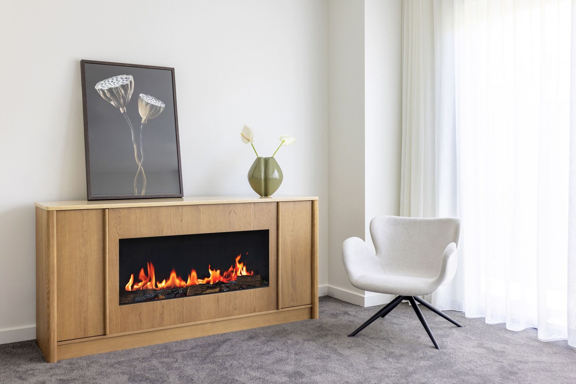 Modern living room with an Ember Arc Grange 180 electric fireplace and a stylish chair, creating a warm and inviting space