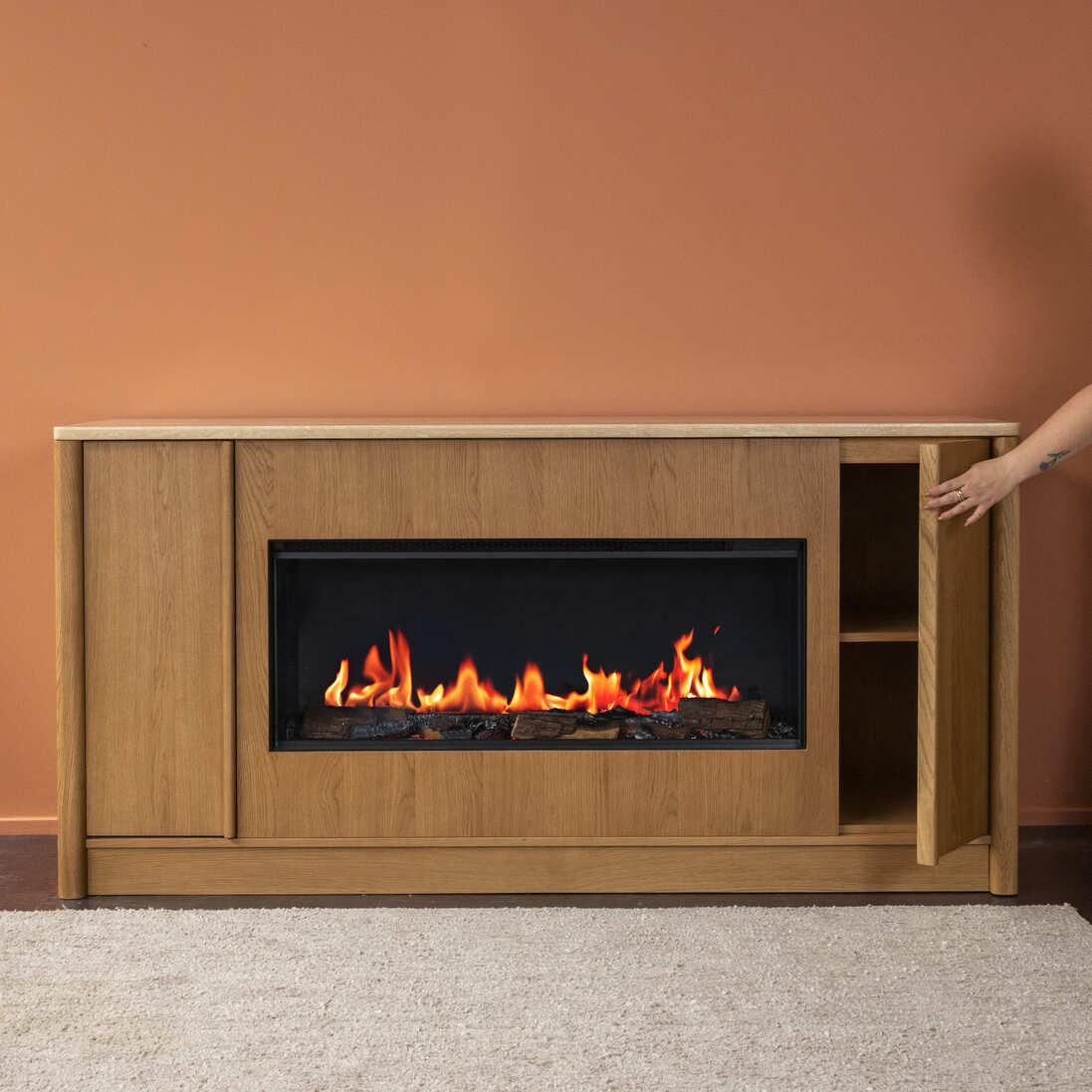 A person stands beside an Ember Arc Grange 180 electric fireplace, enjoying the warmth and comfort it brings to the living space
