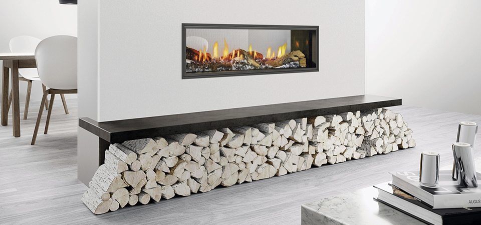 A Heat & Glo Mezzo Series fireplace with logs built into a white wall, offering warmth and style from modern gas log fires for homes