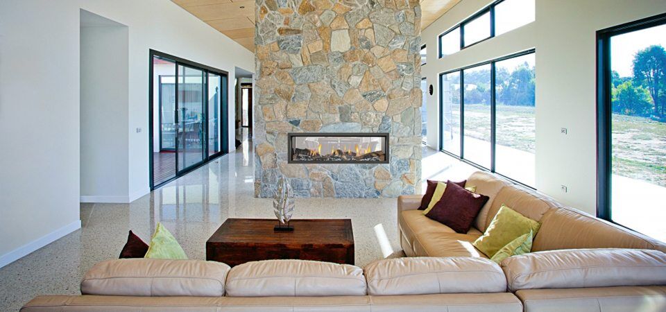 Elegant living room with a Heat & Glo Mezzo Series fireplace set in a stone wall, adding warmth and style with modern gas log fires for homes