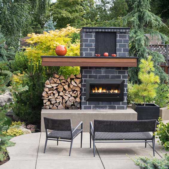 A lush backyard with a Real Flame Fireplaces Exuro and seating area, offering stylish modern gas log fires for homes