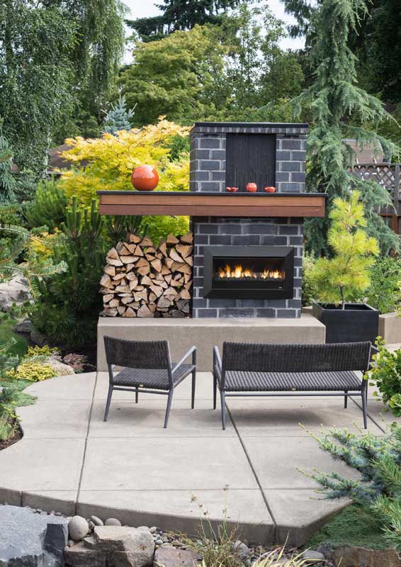 A lush backyard with a Real Flame Fireplaces Exuro and seating area, offering stylish modern gas log fires for homes