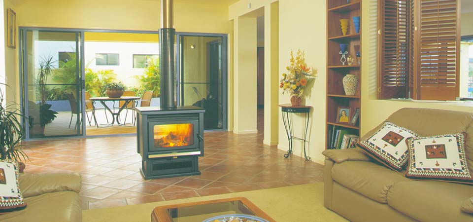 A cosy living room with a Kemlan Coupe Double Sided Freestander, one of the best wood heaters for autumn warmth