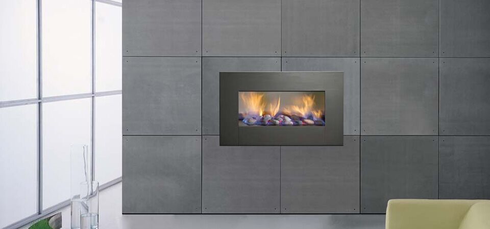 A Horizon Low Line Inbuilt Fire installed in a grey stone wall beside a yellow couch, best gas log heaters for autumn
