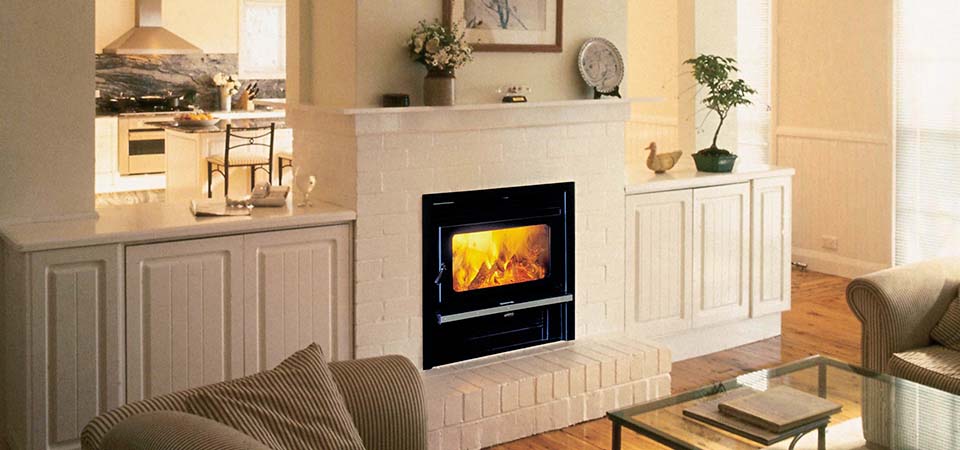 Kemlan Coupe Double Sided Inbuilt stove centered in a cosy room with a traditional fireplace setting, one of the best wood heaters for autumn