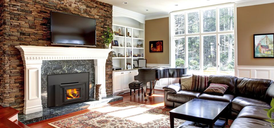 A cosy living room with a Heatilator wood-burning insert topped with a TV, among the best wood heaters for autumn comfort