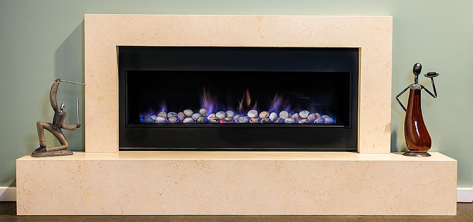 A stone-mantled fireplace with a Horizon Low Line Inbuilt Fire, one of the best gas log heaters for autumn warmth and comfort