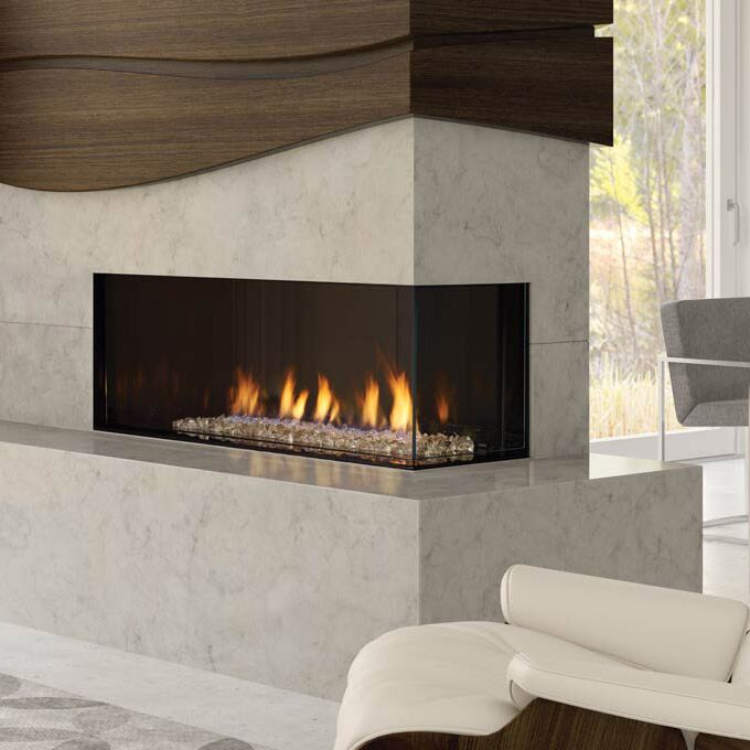 Contemporary gas fireplace with a glass wall, featuring the Regency City Series Chicago Corner 40RE and an adjacent chair