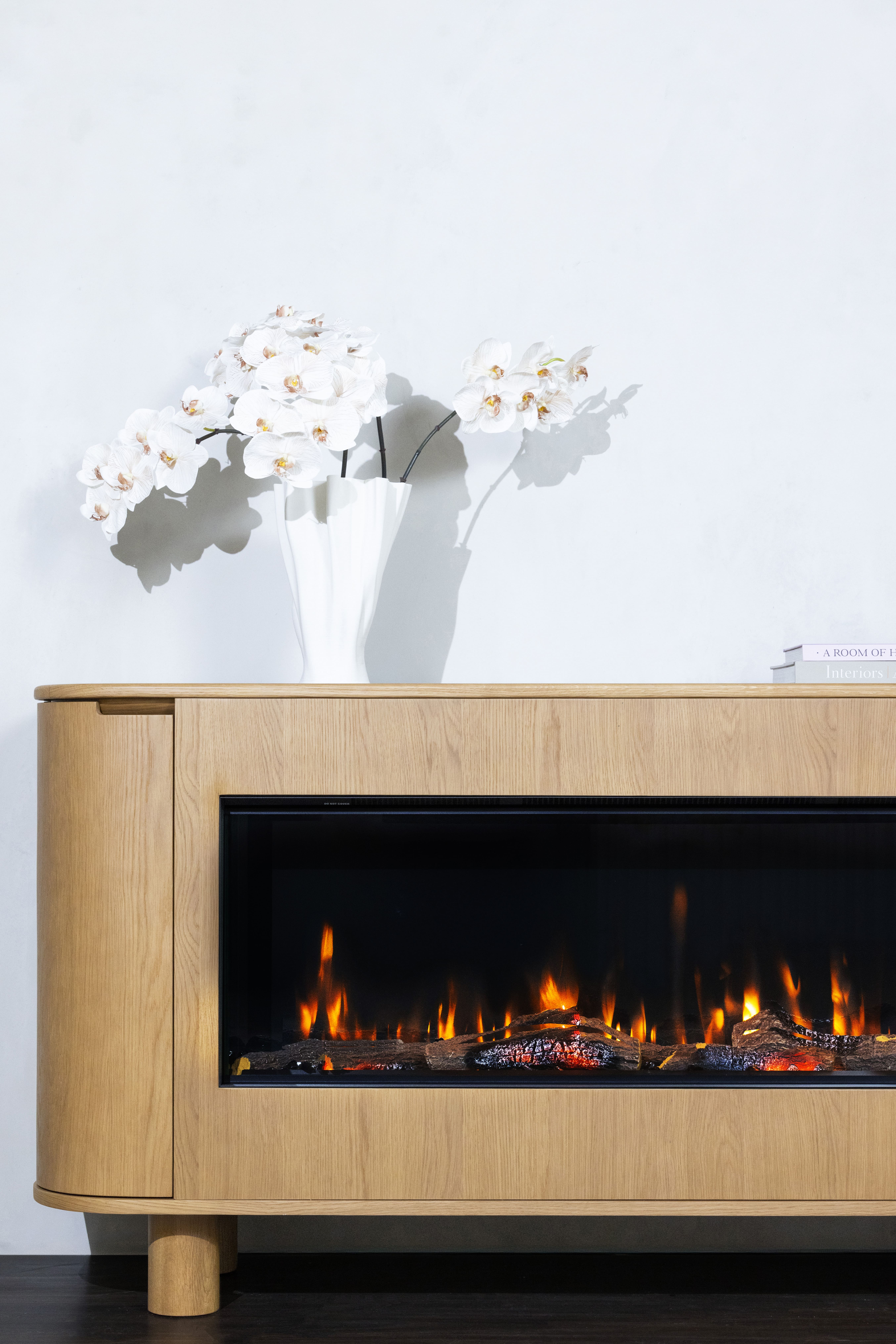 An electric fireplace, featuring a vase of flowers, with the EmberArc Ashton 180 prominently displayed