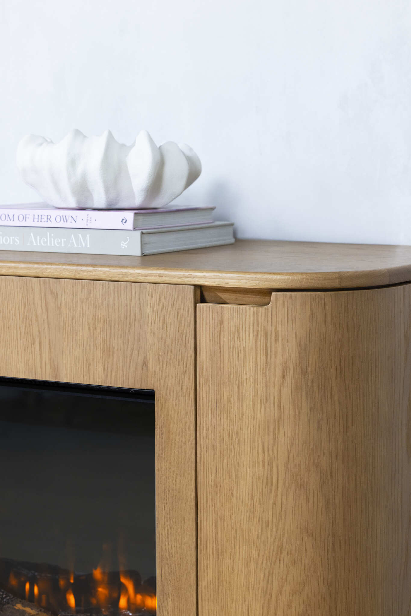 Shell vase placed above the Ember Arc Grange 180 electric fireplace cabinet with a warm fire glowing, adding a cosy touch to the room
