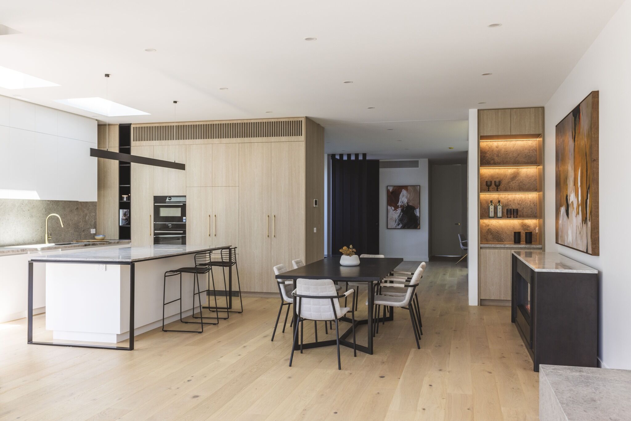 Modern dining room with an electric fireplace and artwork, with the Ember Arc Grange 240 integrated seamlessly into the interior design