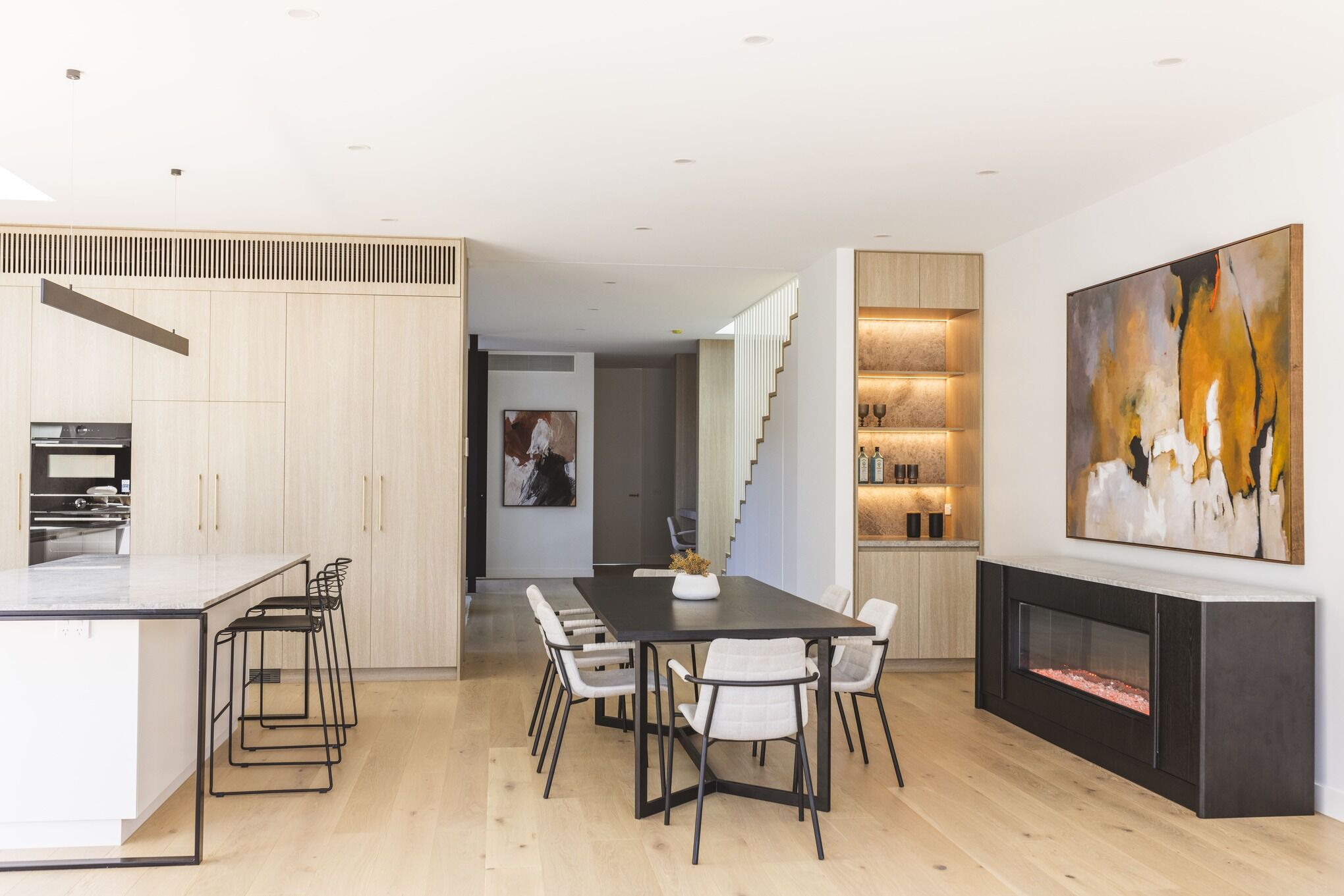 Modern dining room with an electric fireplace and artwork, with the Ember Arc Grange 240 integrated seamlessly into the interior design